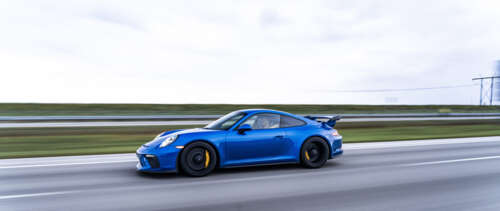 A high-detail shot of a Porsche GT3 RS sports car featuring its iconic aerodynamic... UWUHD wallpaper