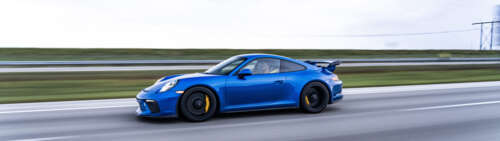 A high-detail shot of a Porsche GT3 RS sports car featuring its iconic aerodynamic... Dual UHD wallpaper for pc download