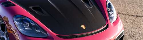 A high-detail shot of a sleek Porsche sports car reflecting light. Dual UHD free wallpaper