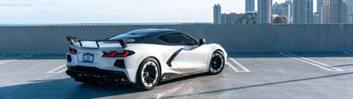 A detailed view of a Chevrolet Corvette C8 sports car, showcasing its aerodynamic... Dual UHD ps4 wallpaper