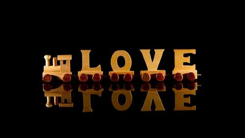 The word 'Love' rendered in 3D wooden letters on a glossy black surface with reflections. wallpaper photo gallery download