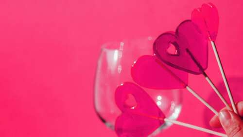 A pink lollipop surrounded by several floating pink hearts on a solid pink background. wallpaper download