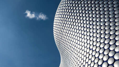A symmetrical modern building with large windows under a clear blue sky. free wallpaper