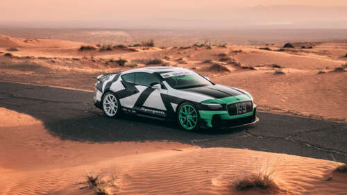 A green 2026 Bentley Continental GT Supersports driving across desert sand dunes. ps4 wallpaper