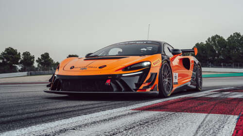 A futuristic McLaren Artura race car driving on a smooth asphalt track wallpaper for laptop download