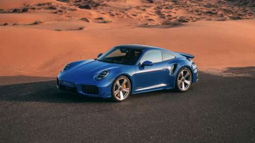A sleek 2026 Porsche 911 Turbo S parked on the sand dunes of a vast desert under... free wallpaper