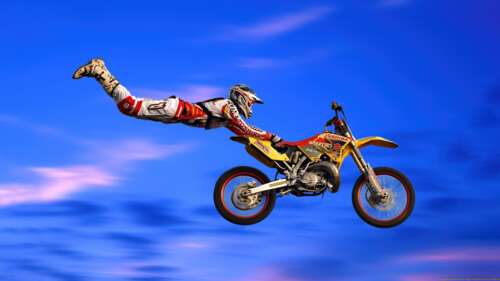 Motocross rider performing a mid-air stunt on a blue Suzuki RM motorcycle against... wallpaper