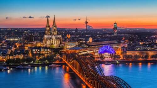 A sunset cityscape of Cologne, Germany, featuring the Cologne Cathedral landmark. wallpaper