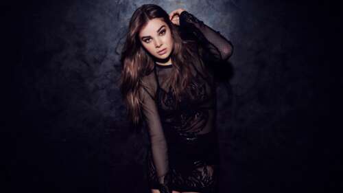 A high-detail portrait of Hailee Steinfeld posing in a black dress against a dark,... free desktop wallpaper