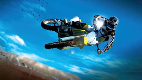 A motocross rider performing a spectacular mid-air stunt on a dirt bike with flying... wallpaper images