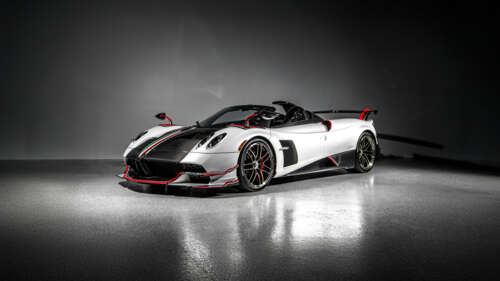 A high-detail close-up of a Pagani Huayra Roadster hypercar against a dark, moody... wallpaper