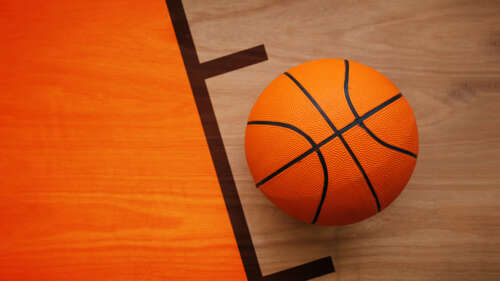 A high-angle view of a polished wooden basketball court showing reflective hardwood... wallpaper