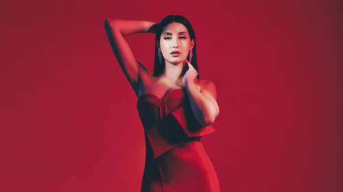 A high-resolution 5K portrait of Nora Fatehi against a striking red background. hd background