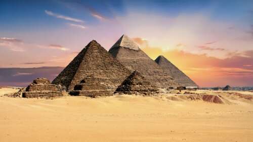 The Great Pyramid of Giza silhouetted against a vibrant orange and purple sunset... free wallpaper