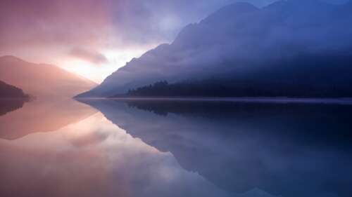 A peaceful landscape of a mountain lake with misty reflections, inspired by the Mac... desktop wallpaper