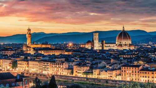 Sunset over an Italian cityscape featuring a historic church and glowing night lights. background images hd