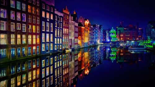 Colorful night view of Amsterdam buildings and canal reflections. free wallpaper