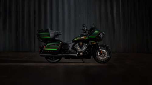 A cinematic close-up of a 2025 Indian Pursuit Elite motorcycle with a dark green... hd background