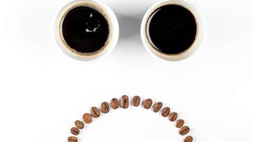 Empty coffee cups and scattered coffee beans on a white background with a sad and... wallpaper