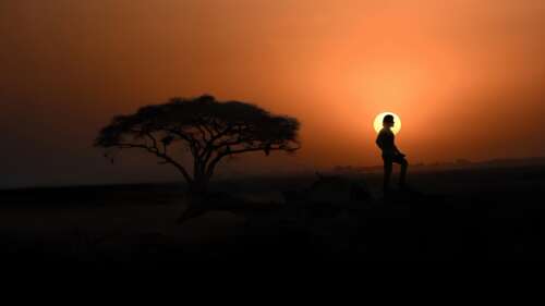 Cinematic silhouette of a person overlooking the Varanasi Ghats during a vibrant... wallpaper download
