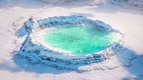 An aerial view of a snow-covered frozen crater lake with icy textures and surrounding... free wallpaper