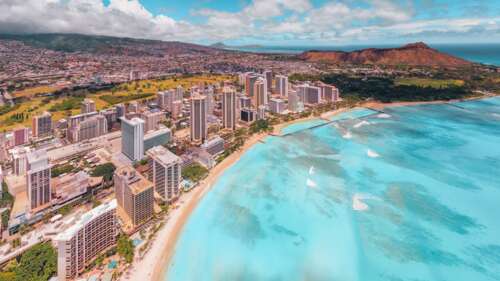 Aerial view of a tropical Hawaiian beach meeting a modern city skyline with blue... free background