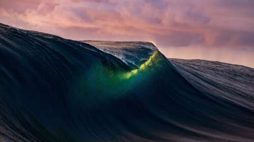 Powerful ocean waves crashing under a dramatic golden sunset sky during a coastal... wallpaper
