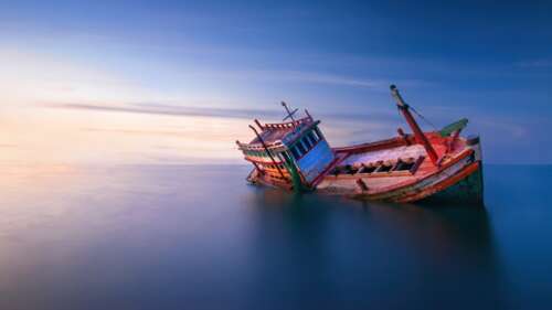 A decaying abandoned fishing boat shipwrecked on the coast during a vibrant twilight... wallpaper