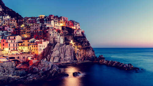 A scenic sunset view of the colorful coastal buildings of Manarola, Cinque Terre,... free wallpaper