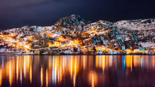 A nighttime view of a Canadian island with warm lights reflecting on the still surface... free background images
