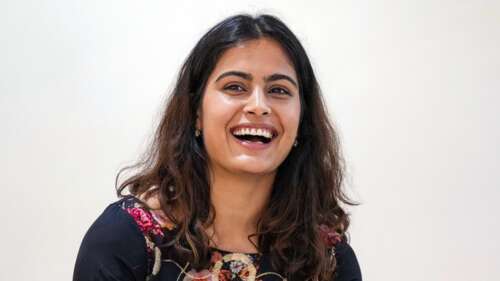 A high-resolution portrait of Indian athlete Manu Bhaker smiling against a white... wallpaper