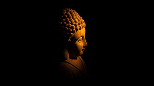 A detailed statue of Gautama Buddha centered against a solid black background, symbolizing... wallpaper