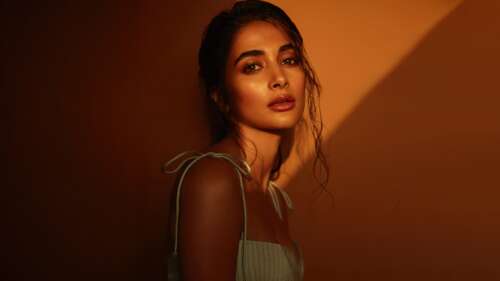 A cinematic portrait of Indian actress Pooja Hegde illuminated by the warm, golden... free wallpaper