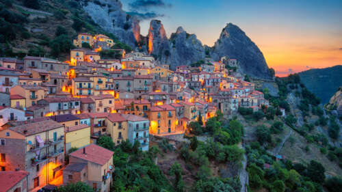 A panoramic view of Italian mountain peaks during a colorful sunset with valley lights... wallpaper