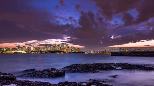 A scenic dusk view of the Sydney, Australia skyline and harbour with glowing city... desktop wallpaper