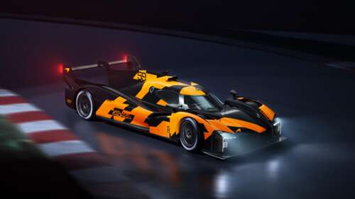 A group of bright orange race cars speeding around a dark race track at night under... wallpaper