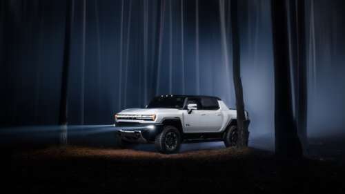 GMC Hummer EV electric vehicle with bright headlights navigating through a thick,... wallpaper download