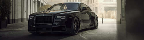 A close-up view of a luxurious black Rolls-Royce Wraith automobile parked in a sophisticated... wallpaper