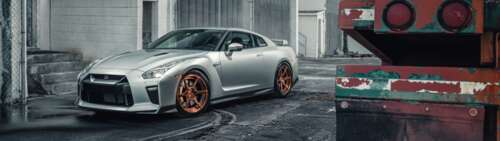 A sleek silver Nissan GT-R supercar featuring a metallic finish and aerodynamic body. Dual UHD free background