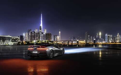 A sleek silver Pininfarina Battista supercar parked on a street in Dubai at night. free wallpaper