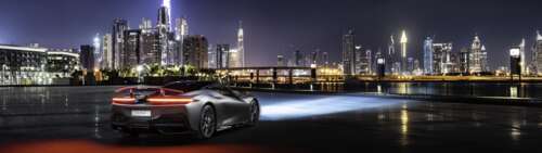 A sleek silver Pininfarina Battista supercar parked on a street in Dubai at night. Dual UHD free hd wallpapers