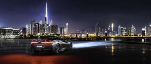 A sleek silver Pininfarina Battista supercar parked on a street in Dubai at night. UWUHD hd background