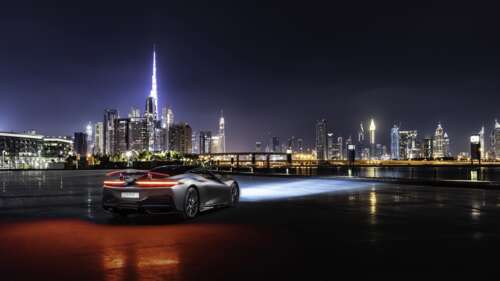 A sleek silver Pininfarina Battista supercar parked on a street in Dubai at night. 8K ps4 wallpaper