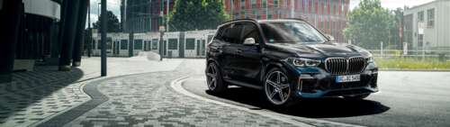 A sleek and shiny black BMW X5 luxury SUV parked in a professional setting. Dual UHD hd background
