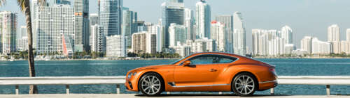 A premium orange Bentley Continental GT showcasing its luxurious design and vibrant... Dual UHD free background images