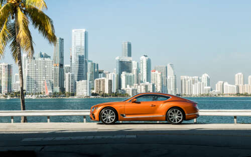 A premium orange Bentley Continental GT showcasing its luxurious design and vibrant... 7680x4800 free background images