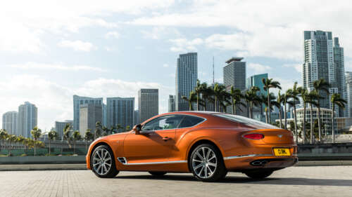 A luxurious orange Bentley Continental GT showcasing its sleek design and vibrant... 8K free wallpaper