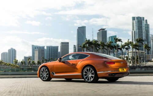 A luxurious orange Bentley Continental GT showcasing its sleek design and vibrant... 7680x4800 desktop wallpaper