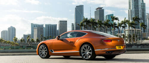 A luxurious orange Bentley Continental GT showcasing its sleek design and vibrant... UWUHD ps4 wallpaper