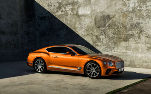 A glossy orange Bentley Continental GT luxury car parked in a scenic setting 7680x4800 wallpaper download